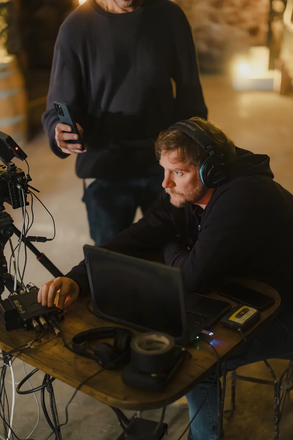 Operador de cámara con auriculares mirando el monitor junto a otra persona